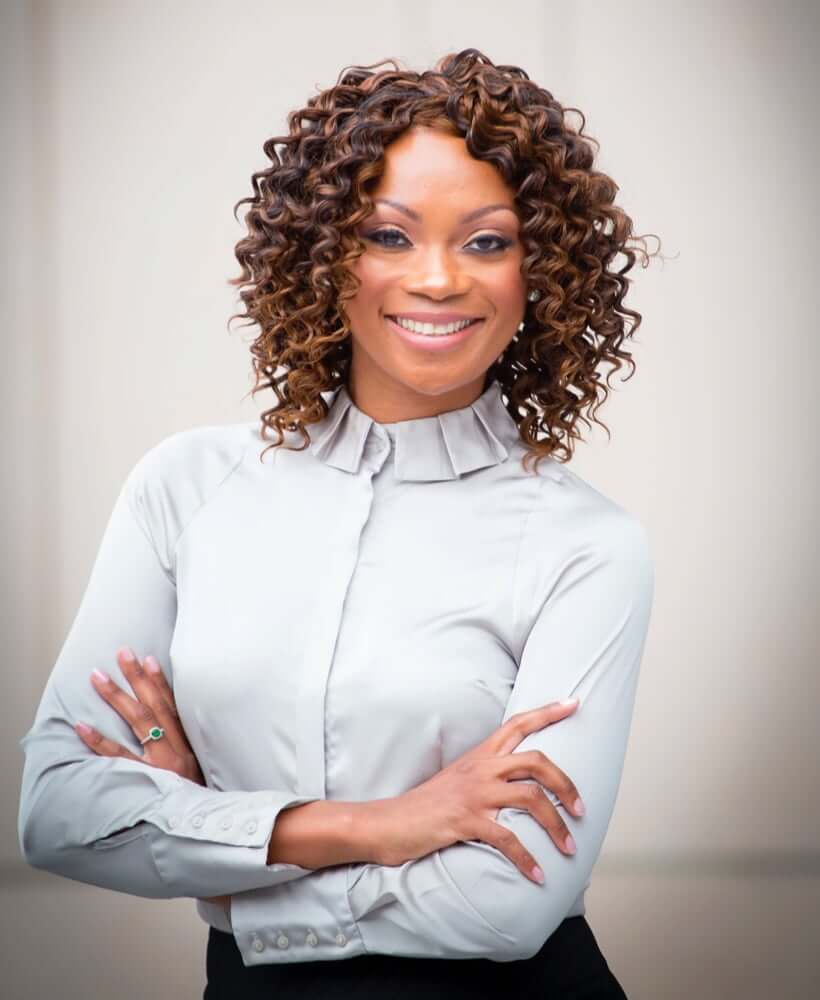 Headshot of Geneviéve standing with her arms crossed smiling and looking into the camera.